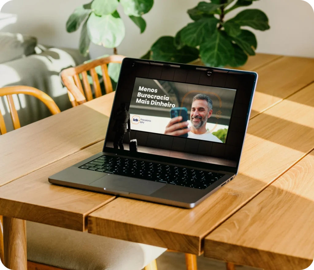 Laptop com tela exibindo "Menos Burocracia Mais Dinheiro" e homem sorrindo